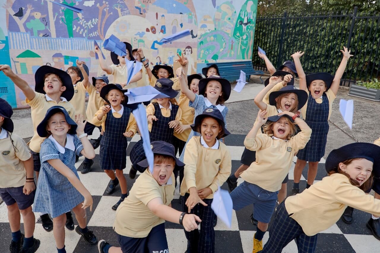 Primary school students playing with paper planes on their school playground.